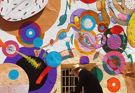 Artista pintando un mural colorido en la pared.