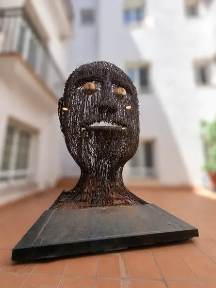 Golden-eyed wire sculpture in soft focus.webp