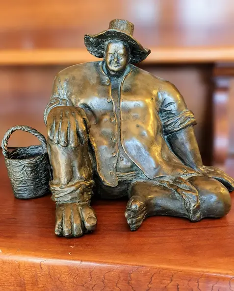 Seated bronze figure with basket.webp