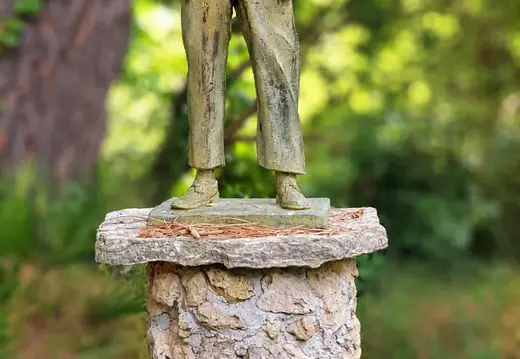 Junger Mann Statue unter Pinienbäumen