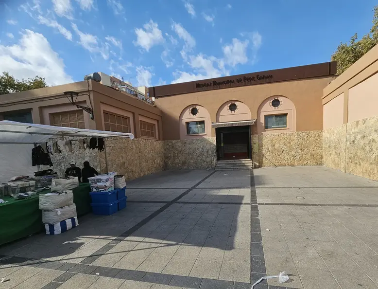 Facade entrance of Mercat Municipal de Pere Garau with market stalls at the left